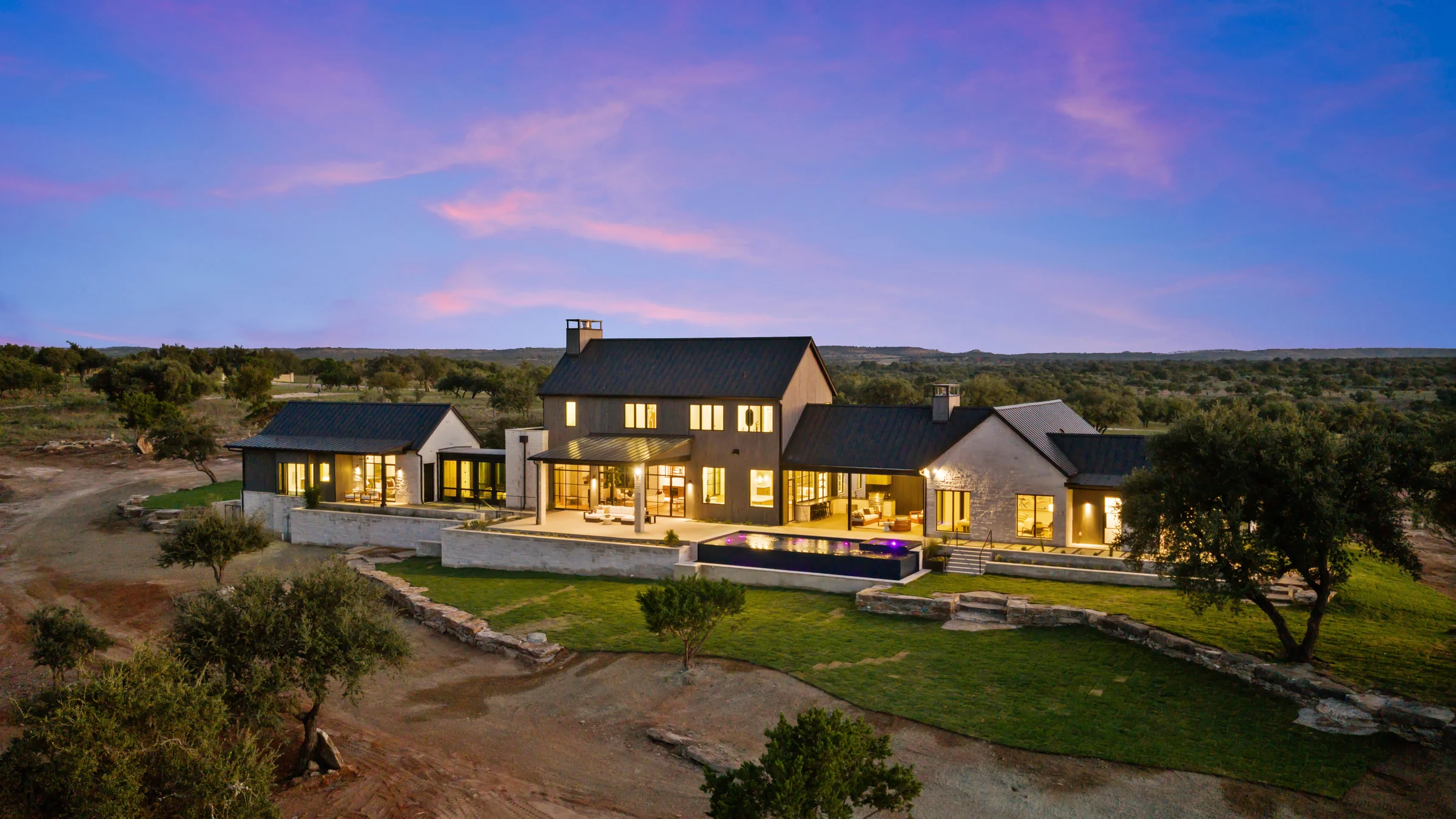 The illuminated Lot 16 residence and pool terrace at dusk.